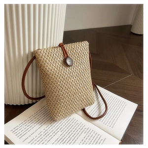 Detail shot of straw woven mini crossbody bag with wooden button closure and slim strap