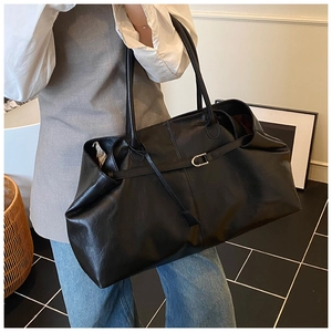 Detail of black large capacity leather tote bag with metal buckle and shoulder straps