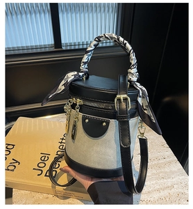 Detailed close-up of color-block bucket bag featuring silk scarf handle and leather strap