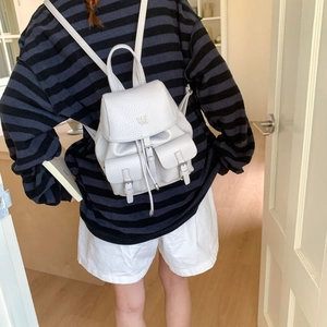 Detail of grey pebble leather backpack with drawstring closure and metal logo on the flap