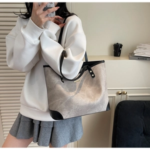 Detail view of large grey tote bag with marble texture and elegant black leather trim