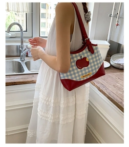 Detail of red and blue checkered tote bag with apple patch and Not Anxious label
