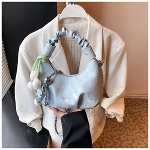 Detail of light blue crescent bag with pleated handle, silver chain and tulip charm