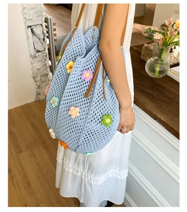 Detail of hand-knitted floral tote bag with colorful 3D flowers and leather straps