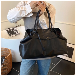 Detail of black large capacity leather tote bag with metallic buckle and shoulder straps