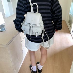 Rear view of model wearing a creamy white faux leather backpack with two front pockets
