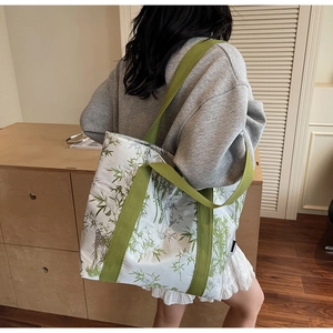 Spacious tote bag with green bamboo leaf print shown carried over the shoulder