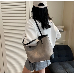 Rear view of a model carrying the large grey tote bag with black straps and reinforced corners