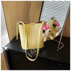 Close-up of pale yellow leather bucket bag with BNML logo and plush dog charm