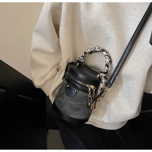 Detail of vintage cylindrical bucket bag with decorative silk scarf and gold lock charm