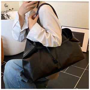 Detailed close-up of large black leather tote bag with soft texture and long strap detail