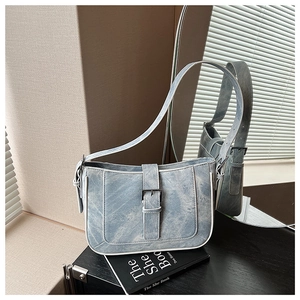 Close-up of light blue washed texture crescent bag with silver buckle and white trim