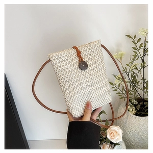 Detail of mini straw phone bag with wood button closure and brown leather shoulder strap