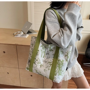Lifestyle shot of large capacity tote bag with green bamboo leaf pattern and wide straps