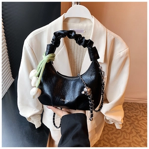 Detail of black embossed crescent bag featuring floral texture and tulip charm