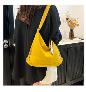 Détail du sac dumpling jaune en nylon avec bandoulière large et cordon de serrage