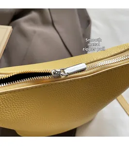 Detail of silver metal zipper on yellow litchi pattern leather handbag with smooth slider