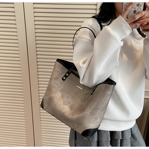 Detail of grey canvas tote bag with black leather trim and elegant gold metal buckle