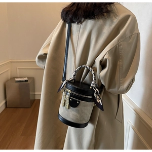 Detail of vintage canvas bucket bag with black leather trim and silk scarf handle