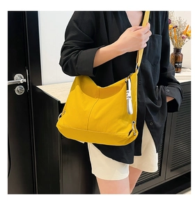Détail du sac besace jaune en nylon avec bandoulière réglable et pendentif décoratif