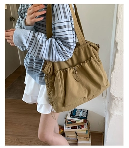Detail der khakifarbenen Shopper-Tasche mit Kordelzug und blau gestreiftem Pullover