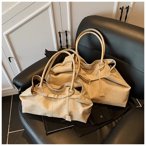 Detail view of large and small beige leather tote bags on a vintage chair