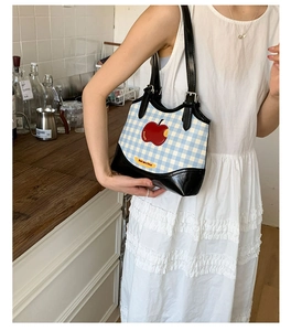 Detail of blue gingham underarm bag featuring a red apple patch and Not Anxious text