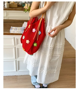 Detail of red crochet tote bag with colorful 3D flowers and brown leather strap