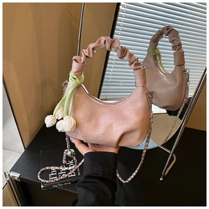 Detailed macro view of pink dumpling bag with pleated handle and tulip floral pendant charm