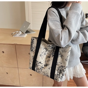 Detail of cream tote bag with black bamboo leaf print styled in home office setting