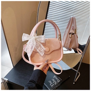 Detail view of pink mini handbag featuring delicate white lace bow and golden hardware