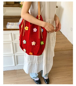 Detail of red crochet tote bag with colorful 3D floral accents and brown leather handles