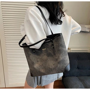 Close-up of a large grey tote bag with marble texture and black leather shoulder straps