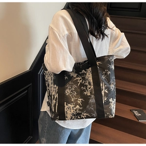Detail of a black canvas tote bag featuring white bamboo patterns and a wide woven strap