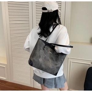 Detail of grey textured tote bag with black leather corners showing large capacity capacity