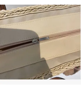 Dettaglio macro della chiusura lampo in metallo liscio su questa borsa tote in paglia