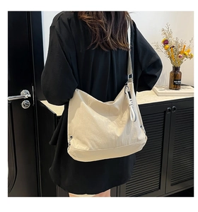 Vue arrière détaillée d'une personne portant un sac hobo en toile beige à large bandoulière