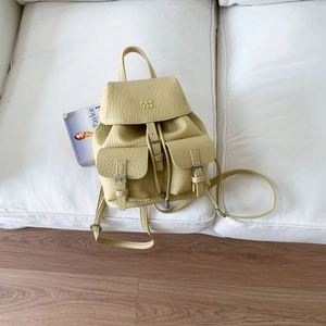 Detail of light yellow lychee grain leather backpack with metal logo and buckle pockets