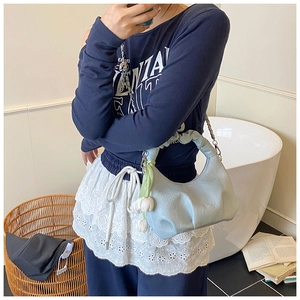 Detail of light blue pleated dumpling bag with silver chain and white floral charm accessory