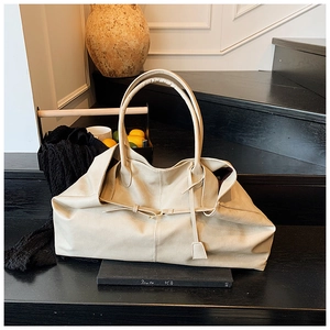 Close-up of beige leather tote bag on black stairs showing soft texture and detail strap
