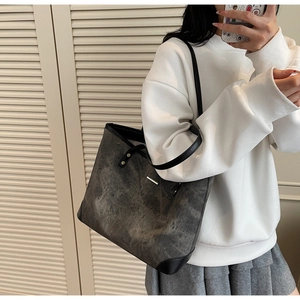 Detail of grey marble pattern tote bag with black straps on a person for daily look