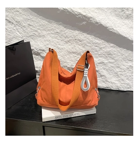 Détail du sac bandoulière orange en nylon avec étiquette tissée et sangle réglable