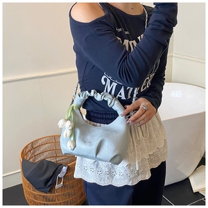 Detail of light blue pleated dumpling bag with tulip charm and silver chain strap