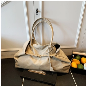 Close-up of beige oversized tote bag with metal buckle and soft leather texture