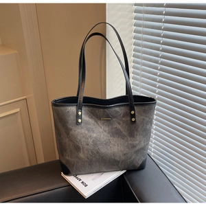 Detail of grey stone-washed tote bag featuring gold metal bar and black handles