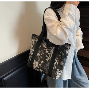 Side view of large shoulder tote bag with black and white bamboo leaf print on model