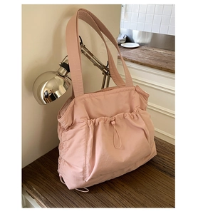 Detail einer rosa gesteppten Nylon-Tote-Bag mit Kordelzugtaschen und breitem Gurt