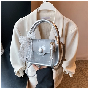 Detail of silver marble textured handbag with white lace bow and round metal buckle closure