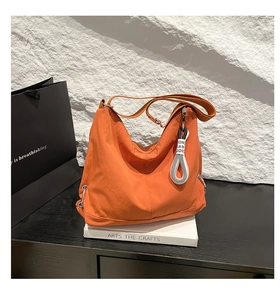 Vue détaillée du sac croissant orange vif avec bandoulière réglable et étiquette lettrée