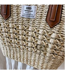 Dettaglio borsa tote in paglia beige con trama a traforo e finiture in pelle marrone